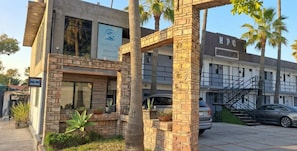 A hotel with a stone facade, a visible entrance, and a staircase leading to the parking area. - Hotel Palmas Quintero (Playas de Rosarito)
