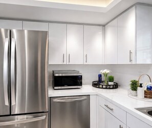A modern kitchen with stainless steel appliances, white cabinets, and a microwave. - Stylish Lake View House: Minutes to Beaches & IMG, Pet-friendly (Bradenton)