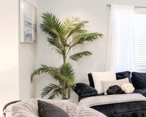 A bedroom with a bed, pillows, a large potted plant, and a wall art piece. - Stylish Lake View House: Minutes to Beaches & IMG, Pet-friendly (Bradenton)
