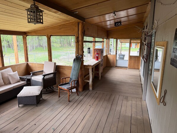 A wooden cabin with a porch, wicker furniture, and a view of the outdoors.