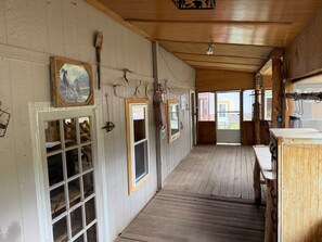 A wooden interior with a wooden floor, a door with glass panels, and a window with a picture frame.