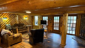 A log cabin interior with a sofa, leather chair, wooden floors, and a fireplace. - Alpine Dream | ATV, Fishing & Mountain Escape (South Fork)
