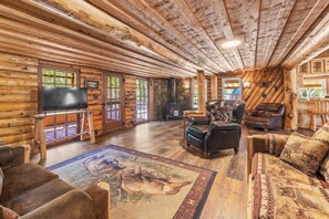 A log cabin interior with a fireplace, leather furniture, and a television. - Alpine Dream | ATV, Fishing & Mountain Escape (South Fork)
