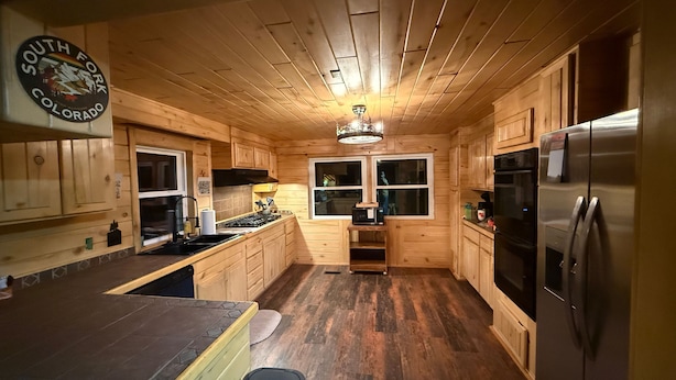 A wooden cabin interior with a kitchen, dining area, and a small living space. - Alpine Dream | ATV, Fishing & Mountain Escape (South Fork)