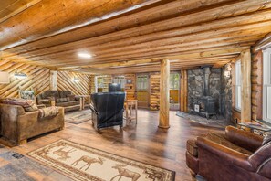 A log cabin interior with a fireplace, leather furniture, and a rug with animal prints. - Alpine Dream | ATV, Fishing & Mountain Escape (South Fork)