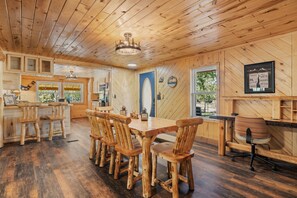 A wooden interior with a dining area, kitchen, and a view of the outdoors. - Alpine Dream | ATV, Fishing & Mountain Escape (South Fork)