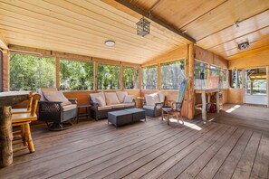 A covered outdoor seating area with wooden furniture and large windows. - Alpine Dream | ATV, Fishing & Mountain Escape (South Fork)