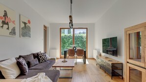 Uma sala de estar moderna com sofá, mesa de centro, televisão e obras de arte nas paredes.