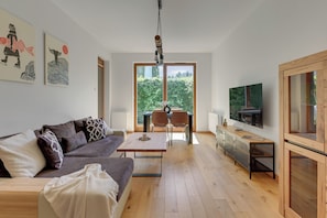 A modern living room with a sofa, coffee table, TV, and artwork on the walls. - Nadmorski Dwór by Grand Apartments (Gdańsk)