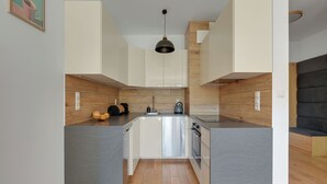 Cozinha moderna com ilha central, detalhes em madeira e luminária pendente.