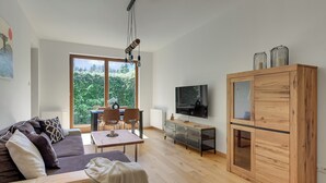 Uma sala moderna com sofá, mesa de jantar, cadeiras, televisão e um armário de madeira.