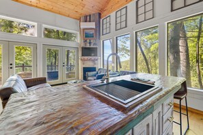 A kitchen with a large island, a built-in grill, and a view of the outdoors. - 20-Acre Cabin • Hot Tub + Fire Pit • 6 Min to Dtwn Clayton • Black Rock Mt (Rabun Gap)