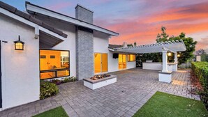 Een modern huis met een terras, een vuurplaats en een pergola.