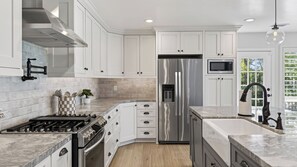 A modern kitchen with white cabinetry, stainless steel appliances, a gas stove, and a built-in microwave.