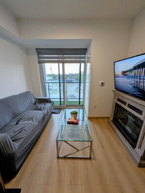 Un salon avec un canapé, une table basse en verre, une cheminée et un téléviseur.