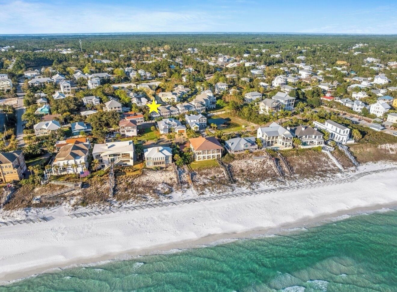 Vista aérea de una zona residencial costera con casas, una playa y aguas turquesas cristalinas.