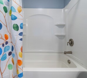 A bathtub with a shower curtain featuring a leaf pattern.