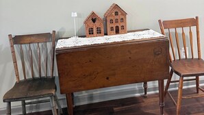 Ein hölzernes Bett mit Spitzenüberwurf, zwei Holzstühle und ein gerahmtes Bild darüber.