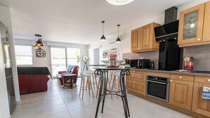 Een moderne keuken met houten kastjes, een zwarte koelkast en een eethoek met krukken.