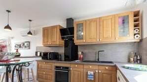 Een moderne keuken met houten kastjes, een zwarte afzuigkap, een magnetron en een vaatwasser.
