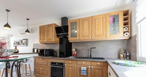 A modern kitchen with wooden cabinets, a black range hood, a microwave, and a dishwasher.