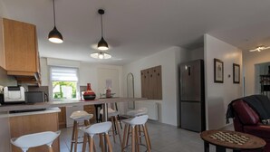 Een moderne keuken met een centraal eiland, barkrukken, een koelkast en een schaakspel.
