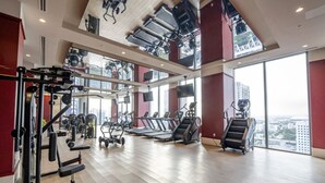 A gym with treadmills, weight machines, and a view of the city.