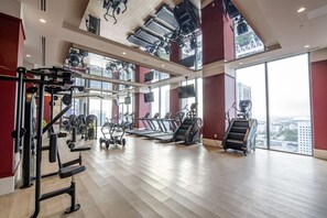 Ein Fitnessstudio mit Laufbändern, Krafttrainingsgeräten und Blick auf die Stadt.