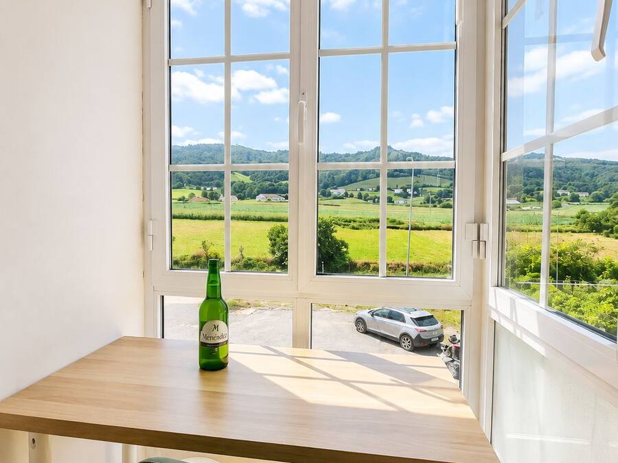 Una habitación con un ventanal grande, una mesa de madera y una silla verde.