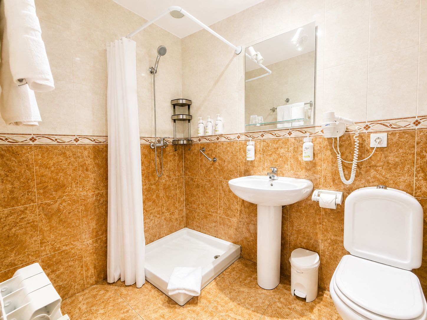 A bathroom with a shower, sink, toilet, and a mirror.
