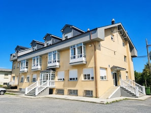 Un edificio residencial de varios pisos con balcones, una escalera y un garaje.