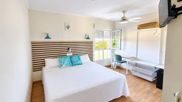 A hotel room with a bed, desk, chair, and a window with blinds.