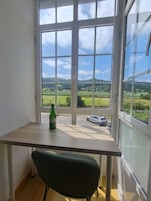 A room with a view of a green landscape through a large window.