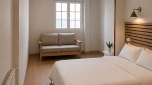 A bedroom with a bed, a nightstand, a window, a ceiling fan, and a wall-mounted lamp. - Hotel Peña Pintada (Valdes)