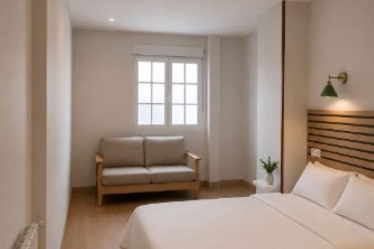 A bedroom with a bed, a nightstand, a window, a ceiling fan, and a wall-mounted lamp.