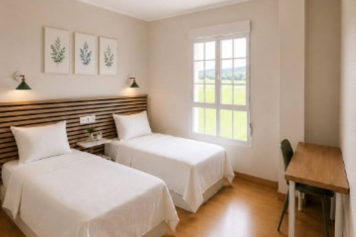 A bedroom with two beds, a ceiling fan, a window with a view, and a small table.