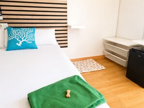 A hotel room with a bed, a nightstand, a desk, a chair, and a small kitchenette. - Hotel Peña Pintada (Valdes)