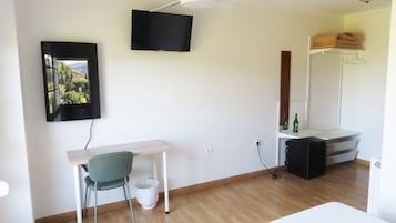 A room with a desk, chair, television, and a wardrobe.