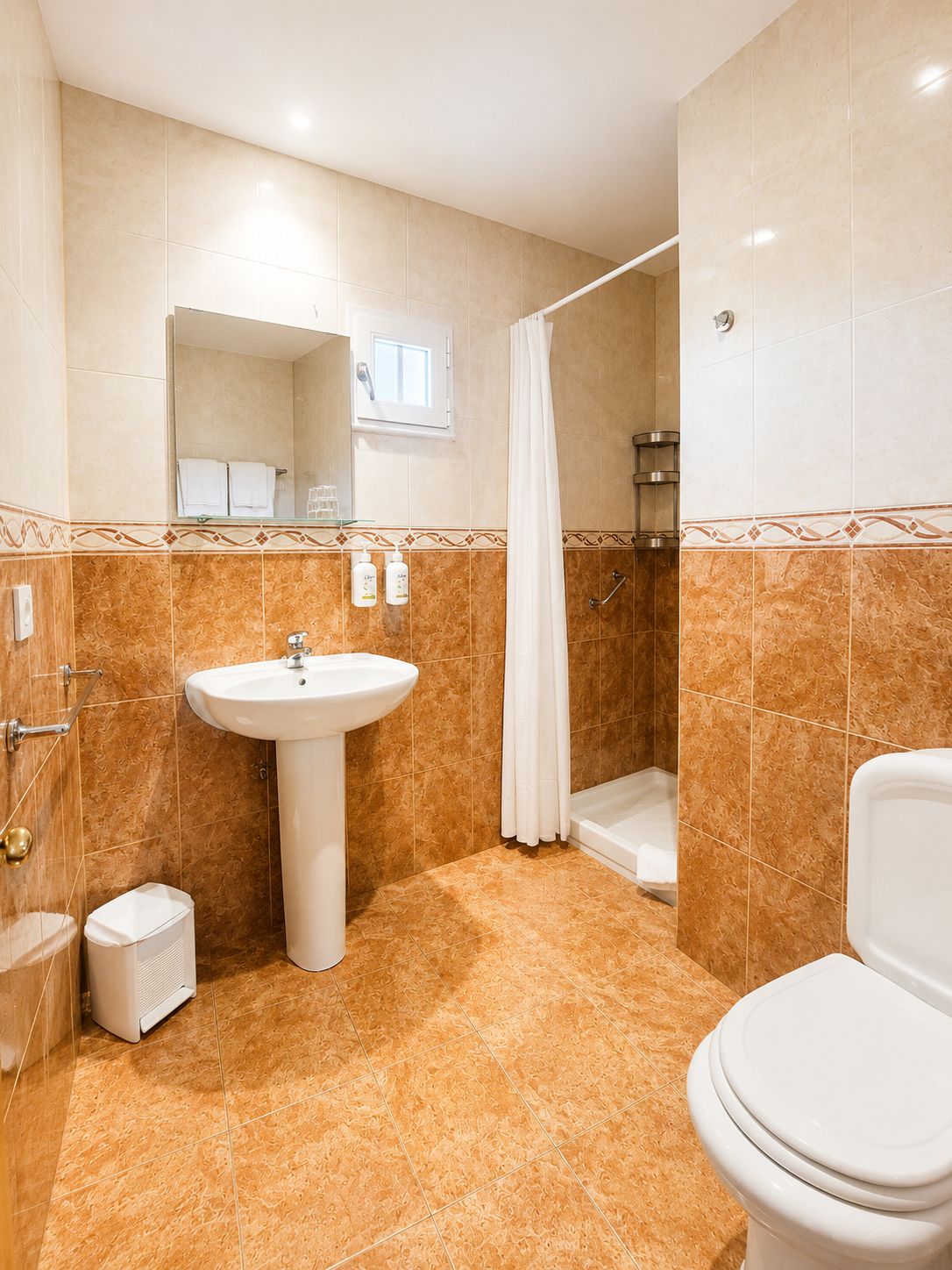 Un baño con lavamanos, inodoro, ducha y espejo.