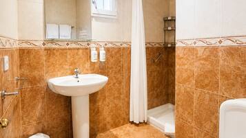 Un baño con lavamanos, inodoro, ducha y espejo.
