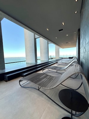 A modern outdoor seating area with a view of the sea, featuring metal chairs and tables, and a concrete floor. - Studio Luxo Vista Lago Design Jalapão (Palmas)
