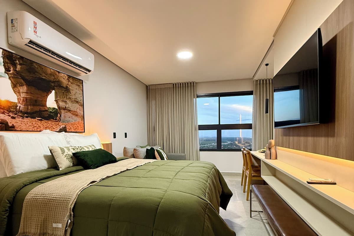 Ett modernt hotellrum med en stor säng, ett skrivbord, en platt-TV och utsikt över staden.