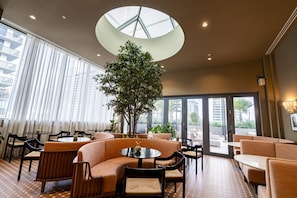 Eine moderne Lounge mit runden Tischen, Sofas und einem großen Baum.