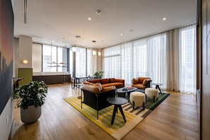 Ein geräumiges Wohnzimmer mit großem Fenster, einer Sofagarnitur, einem Couchtisch und einer Topfpflanze.
