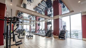 Un'ampia palestra con diverse attrezzature per esercizi, grandi finestre e un soffitto alto.