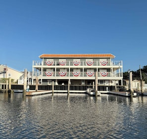 A multi-story waterfront building with balconies and a dock area.
