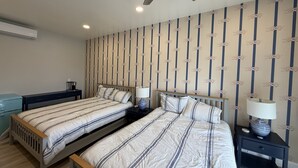 A bedroom with two beds, a ceiling fan, and a patterned wallpaper. - Relaxing Coastal Retreat in Cape May! Condo #8 (Cape May)