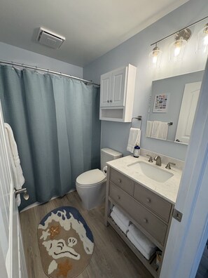 A bathroom with a shower curtain, toilet, sink, and towel rack.