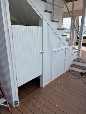 A wooden deck with a white door and a staircase leading to an upper level.