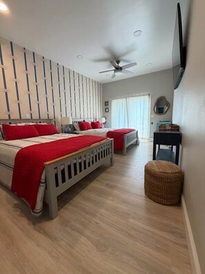 A bedroom with two beds, a ceiling fan, a television, and a window with curtains. - Cape May Harbor Suite, 2 Queens + King Bedroom, Kitchenette (Cape May)